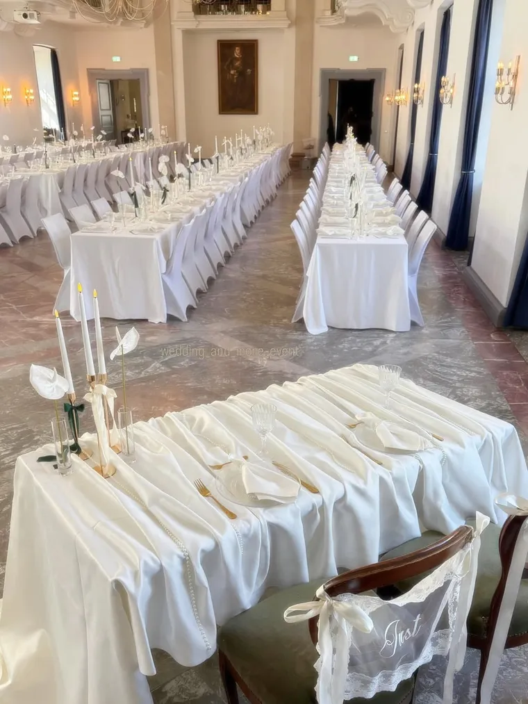 Bankettsaal mit weißer Tischdekoration und Draperie